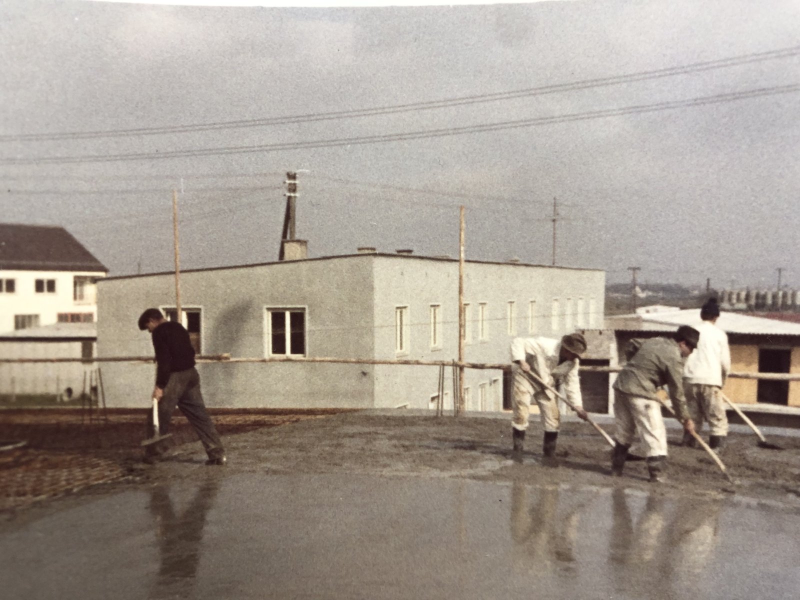 Historische Farbaufnahme: Weishaupt-Bauarbeiter beim Ausbringen von Beton auf einer Bodenplatte
