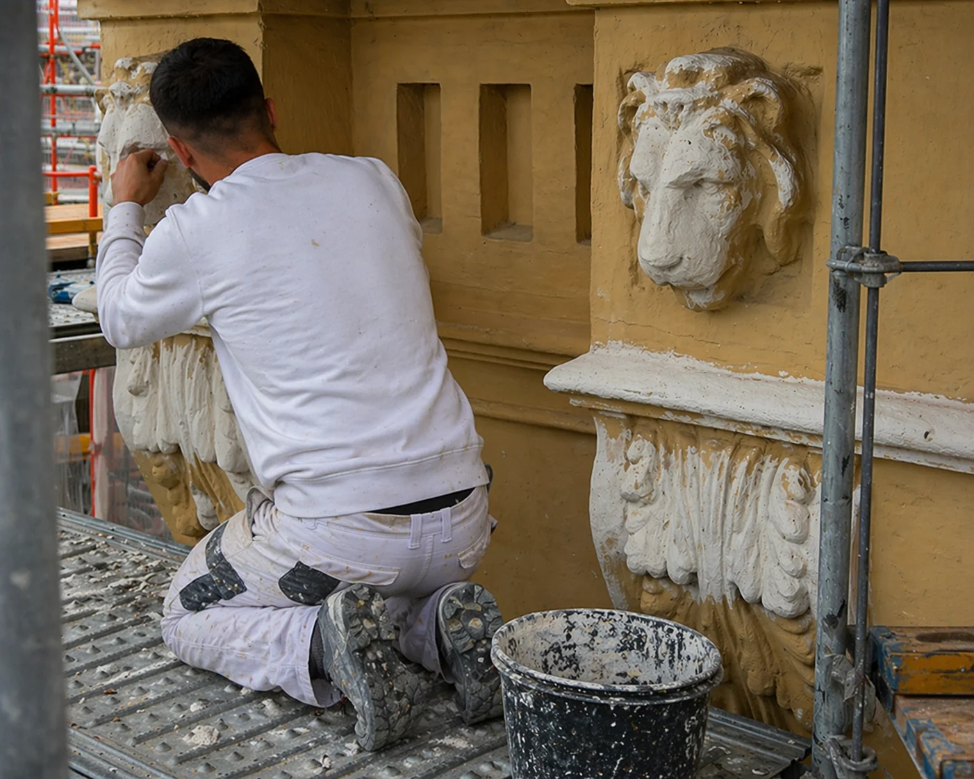 Restaurator bei der Arbeit an ornamentalen Löwenkonsolen einer historischen Fassade in Augsburg